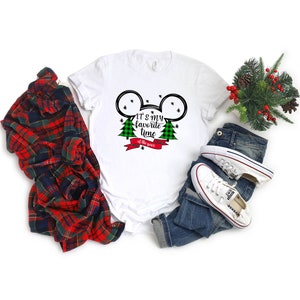 Puede incluir: Camiseta blanca con una silueta de Mickey Mouse en blanco y negro con &aacute;rboles de Navidad de cuadros verdes y negros y una cinta roja con el texto "Es mi &eacute;poca favorita del a&ntilde;o".