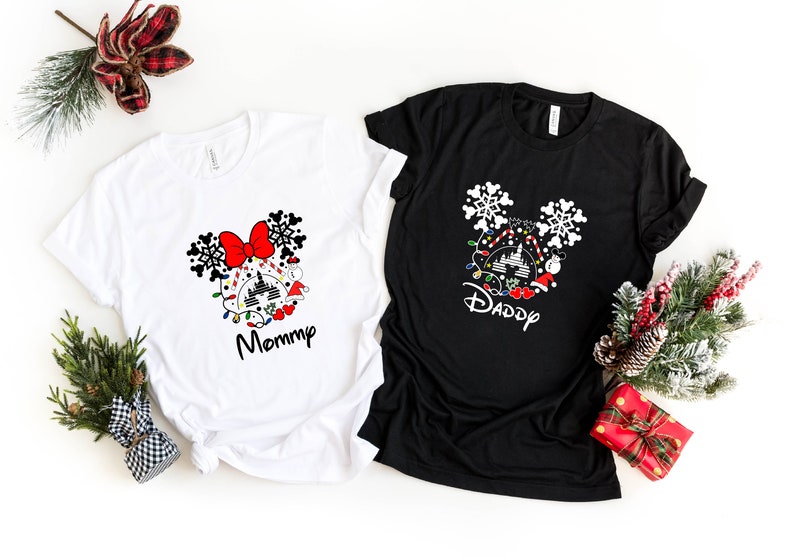 May include: Two white and black t-shirts with a Christmas Mickey Mouse design. The white shirt says "Mommy" and the black shirt says "Daddy".