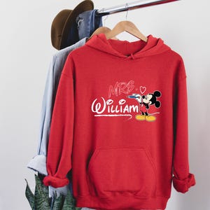 May include: Red hooded sweatshirt with a white Mickey Mouse design and the text "MRS. (heart) WILLIAM" in pink.