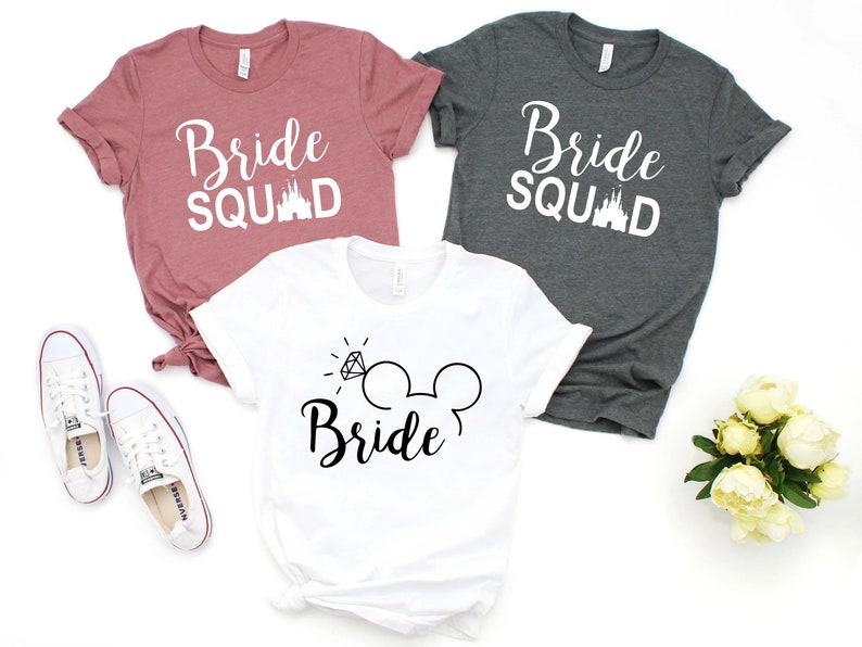 May include: Three t-shirts with the text "Bride Squad" and a Disney castle graphic. The white t-shirt has a diamond ring and Mickey Mouse ears with the text "Bride".