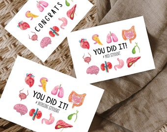 May include: Three white greeting cards with colorful anatomical illustrations of organs. The cards say "Congrats", "You Did It! #Nursing Student", and "You Did It! #Med Student".