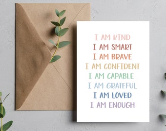 May include: A white card with the text "I am kind, I am smart, I am brave, I am confident, I am capable, I am grateful, I am loved, I am enough" printed in rainbow colors.