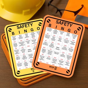 Puede incluir: Dos tarjetas de bingo de seguridad, una amarilla y otra naranja, con texto negro y borde negro. Las tarjetas tienen frases y números relacionados con la seguridad. Una pila de tarjetas similares está debajo. Equipo de seguridad en el fondo.