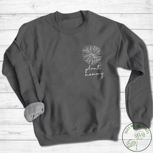 May include: A dark grey sweatshirt with a white outline of a monstera leaf and the text "plant mommy" on the front.