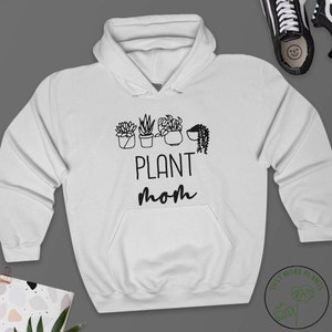 May include: White hooded sweatshirt with black text that reads "PLANT mom" and a graphic of four potted plants.