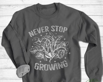 May include: A dark gray sweatshirt with a white graphic design that says "Never Stop Growing" with a drawing of a plant with three vegetables.