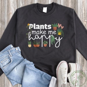 May include: Black sweatshirt with white text that reads "Plants make me happy". The text is surrounded by small illustrations of potted plants.