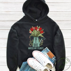 May include: Black hoodie featuring a graphic of a watering can with a bouquet of red tulips and the text "If I Die Water My Plants".