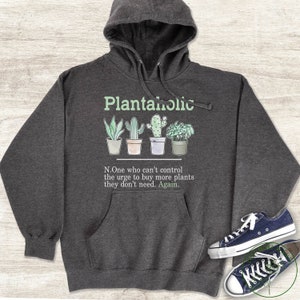 May include: A dark grey hoodie with a white graphic that says "Plantaholic" and a definition of the word. The graphic includes four potted plants, including a cactus and a succulent.