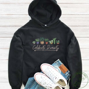 May include: Black hoodie featuring a graphic of potted plants and the text "Celebrate Diversity".