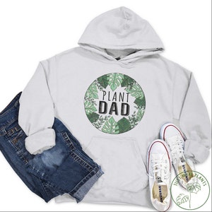 May include: White hooded sweatshirt with a green and black graphic of a circle with the text "Plant Dad" surrounded by leaves.