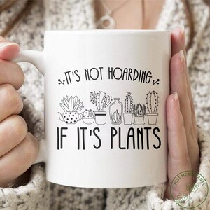 Op de afbeelding: Witte keramische koffiemok met een zwarte omtrek van potplanten en de tekst "Het is geen hamsteren als het planten zijn".