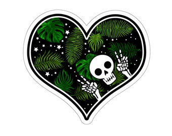 May include: A black heart-shaped design with a white skull and bones making a peace sign. The background is filled with green tropical leaves and white stars.