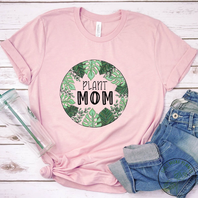 May include: A pink t-shirt with a green circle design featuring various leaves and the text "Plant Mom".