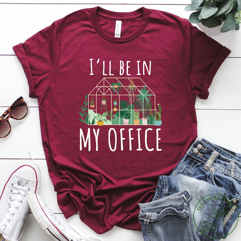 May include: A maroon t-shirt with the text "I'll be in my office" and a graphic of a greenhouse with plants.