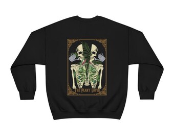 May include: Black sweatshirt with a graphic print of two skeletons with plants growing out of their ribcages. The graphic is framed in a gold border and includes the text "The Plant Lover".
