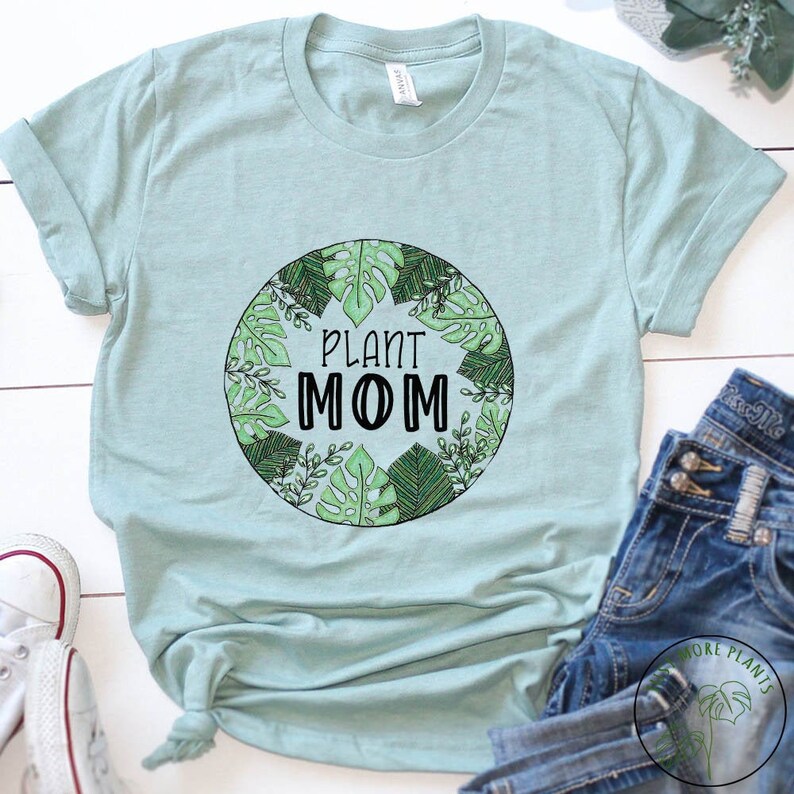 May include: A light blue t-shirt with a green circle design featuring a variety of leaves and the text "Plant Mom".