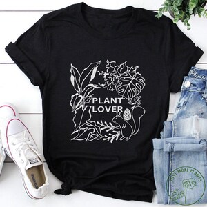 May include: Black t-shirt with a white graphic of plants and a squirrel. The text "Plant Lover" is in the center of the graphic.