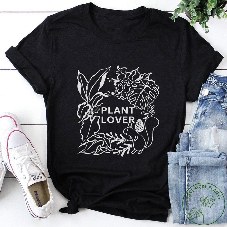May include: Black t-shirt with a white graphic of plants and a squirrel. The text "Plant Lover" is in the center of the graphic.
