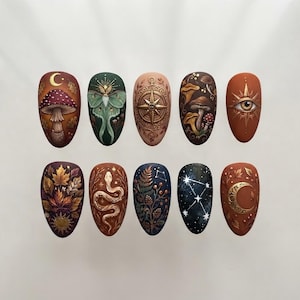 Peut inclure: Un ensemble de dix faux ongles décorés d'illustrations détaillées, notamment un champignon avec un croissant de lune, un papillon de nuit vert, une boussole dorée, divers champignons, un œil, des feuilles d'automne, un serpent, des fougères, un ciel étoilé et une lune.
