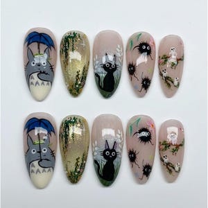 Puede incluir: Juego de diez u&ntilde;as postizas en forma de almendra, cada una pintada a mano con un dise&ntilde;o diferente. Los dise&ntilde;os incluyen un personaje de dibujos animados gris bajo un paraguas azul, un gato negro y otras ilustraciones caprichosas sobre un fondo nude.