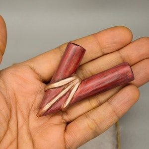 May include: A red and copper colored ceramic pipe with a unique design. The pipe is shaped like a V and has a copper band around the middle.