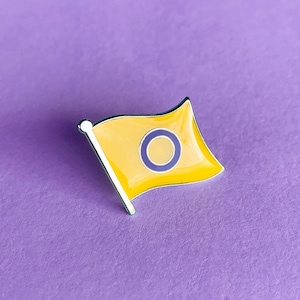 Pode incluir: Uma bandeira amarela com um círculo roxo e um contorno branco no centro. A bandeira está sobre um fundo roxo.
