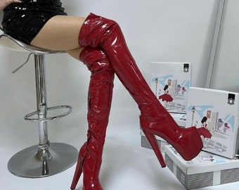 Könnte beinhalten: Ein Paar rote, lackierte Oberschenkel-Stiefel mit Plateau und Stiletto-Absatz.