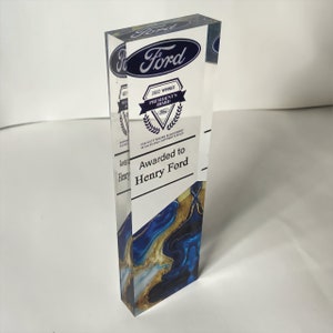 May include: A clear acrylic award with a blue and gold marbled design. The award features the Ford logo, the text "2022 Winner President's Award", and the text "Awarded to Henry Ford".