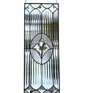 Puede incluir: Panel rectangular de vidriera con borde negro y diseño ovalado central. El panel presenta vidrio transparente y texturizado con un motivo floral en el centro y formas de diamante decorativas en la parte superior e inferior. Cuelga de una cadena.