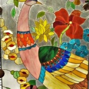 May include: Stained glass panel featuring a colorful peacock with a pink neck, orange and blue accents, and yellow and blue tail feathers. The artwork includes flowers in red, yellow, and blue, with green leaves and a silver background. Decorative art.