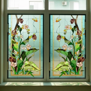 Puede incluir: Ventana de vidrieras con diseño floral. La obra de arte presenta una disposición simétrica de flores en tonos rosa, marrón y amarillo, con hojas y tallos verdes. El fondo es azul claro con un patrón de cuadrícula.