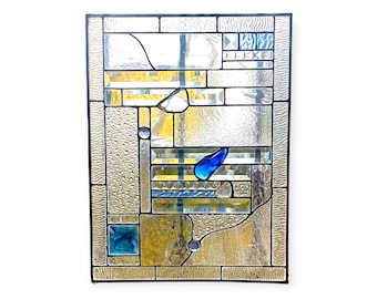 May include: A stained glass window panel with a geometric design featuring blue, clear, and yellow glass pieces.