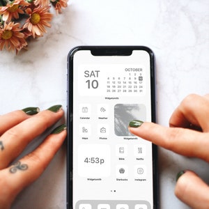 May include: A smartphone displaying a calendar widget with the date "SAT 10" and the month "OCTOBER". The calendar shows the dates 1 through 31. The phone also displays a clock with the time "4:53p".
