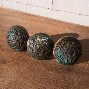 May include: Three antique door knobs with intricate floral designs in shades of brown and green.