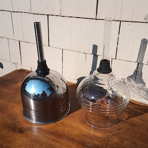 May include: Two glass and metal pour spouts. One is silver with a metal tube and the other is clear glass with a glass tube.