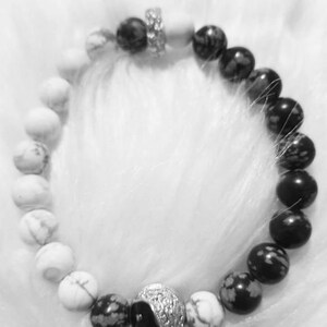 Puede incluir: Un brazalete de cuentas yin yang en blanco y negro con piedras blancas y negras. El brazalete tiene un cierre plateado.
