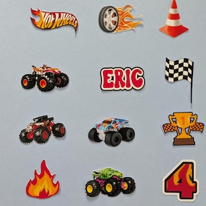 May include: A collection of colorful Hot Wheels-themed stickers. Includes a flaming tire, a red and white traffic cone, monster trucks, a checkered flag, a trophy, a flame, and the name "ERIC".