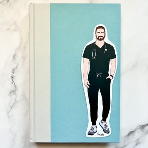 May include: A sticker featuring a male medical professional in dark green scrubs, a stethoscope, and a watch. The sticker is placed on a light blue background, with the name "Jacob" at the bottom. The sticker is on a book.