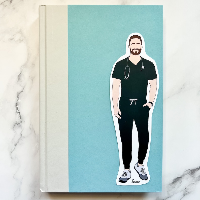 May include: A sticker featuring a male medical professional in dark green scrubs, a stethoscope, and a watch. The sticker is placed on a light blue background, with the name "Jacob" at the bottom. The sticker is on a book.