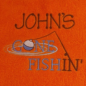 May include: An orange textured fabric featuring dark brown embroidered text that reads JOHN'S, followed by a light blue embroidered fishing bobber and line, with the light blue embroidered text GONE FISHIN' below it.