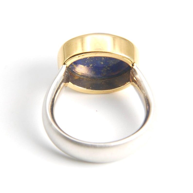 May include: A gold and silver ring with a blue lapis lazuli stone set in the center.