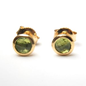 Può includere: Un paio di orecchini a bottone dorati con accenti di pietre preziose verdi.