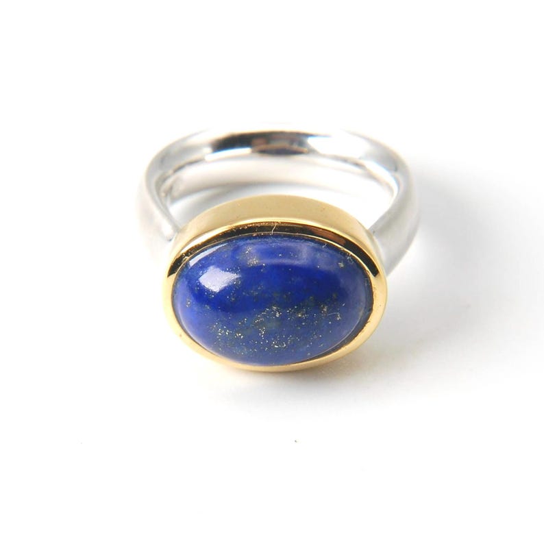 May include: A silver ring with a gold setting and a blue oval lapis lazuli gemstone.