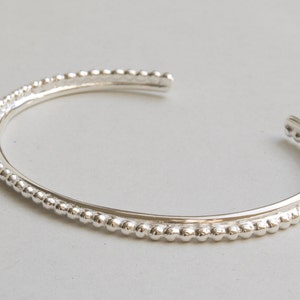 May include: A silver bangle bracelet with a beaded edge.