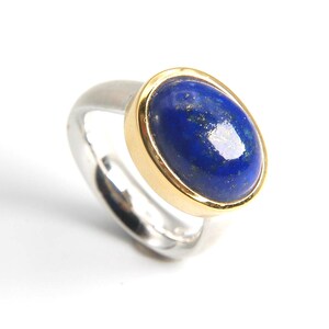 May include: A silver ring with a gold band set with a blue oval lapis lazuli gemstone.