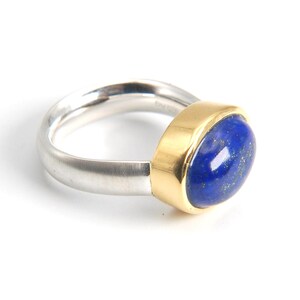 May include: A silver and gold ring with a blue oval lapis lazuli gemstone.