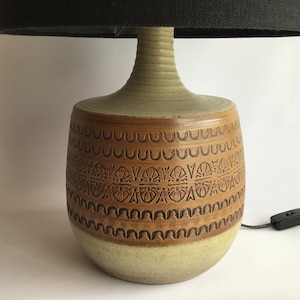 Könnte beinhalten: Eine Keramik-Tischlampe mit einem braunen und weißen gemusterten Sockel und einem schwarzen Lampenschirm.