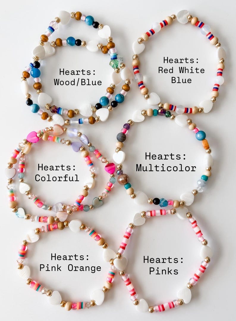 May include: Six circular beaded bracelets featuring white heart-shaped beads and various colored accents. The bracelets are labeled as Hearts: Wood/Blue, Red White Blue, Colorful, Multicolor, Pink Orange, and Pinks, showcasing diverse bead styles.