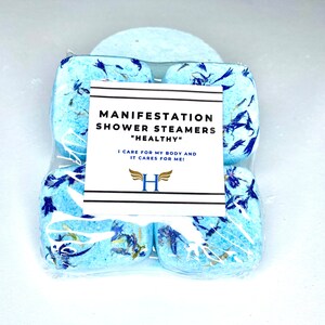 K&ouml;nnte beinhalten: Vier blaue Duschdampfer mit wei&szlig;en und blauen Bl&uuml;tenbl&auml;ttern, verpackt in durchsichtigem Plastik. Das Etikett lautet "Manifestation Shower Steamers "Healthy" I care for my body and it cares for me! H"